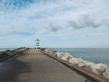 Lighthouse amidst sea and buildings against sky