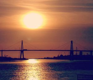 Suspension bridge over sea during sunset