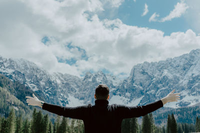 Rear view of hiker with arms outstretched against dramatic sky