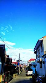 Cars on street in city against blue sky