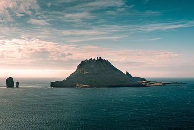 Mountain at sea against sky during sunset