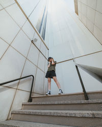 Low angle view of woman on staircase against wall