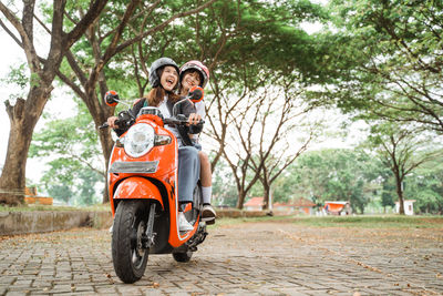 Portrait of woman riding motor scooter on road