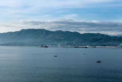 Scenic view of sea by mountains against sky