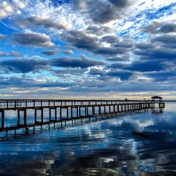 Pier on sea against cloudy sky