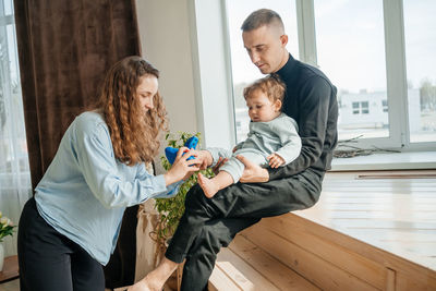 Mom and dad put shoes on the baby. high quality photo