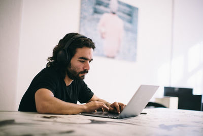 Young man looking at camera while sitting on table at home