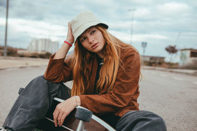 Young woman wearing hat sitting outdoors