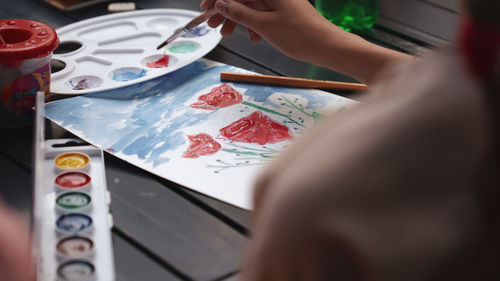 Midsection of woman holding painting on table