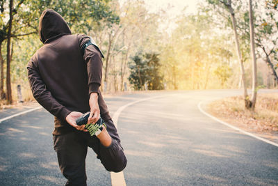 Man stretching leg on road