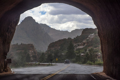 Road amidst trees and mountains against sky