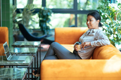 Young woman sitting on sofa at home