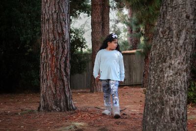 Girl standing by trees in forest