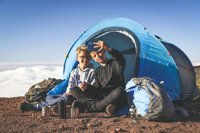 Brothers taking selfie while camping on mountain