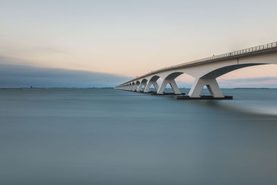 Bridge over river against sky during sunset