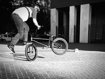 Side view of man riding bicycle on footpath