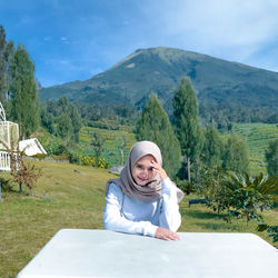 Portrait of smiling young woman against mountain