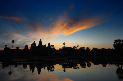 Scenic view of lake by angkor wat against sky during sunset