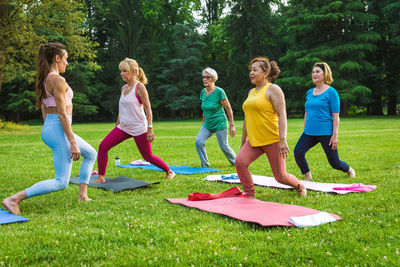 Side view of friends exercising on field