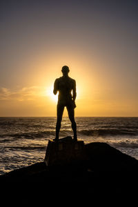 Silhouette man looking at sea against sky during sunset