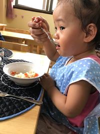 Side view of girl eating food at table