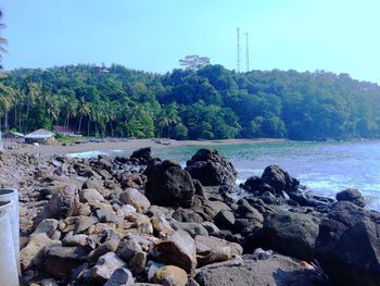 Rocks by sea against clear sky