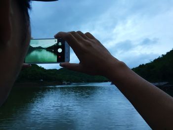 Midsection of person photographing against sky