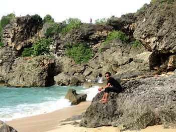 Side view of man on rock at beach