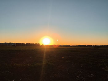 Scenic view of field against clear sky during sunset