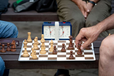 Midsection of men playing chess by clock on table