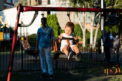 Cute girl with man swinging in playground