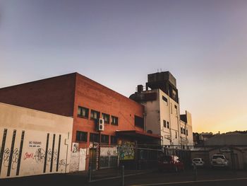 Cars on road by buildings against clear sky