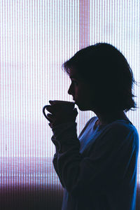 Side view of young woman drinking coffee