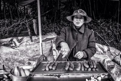 Old women cooking sausages to sell at market stall