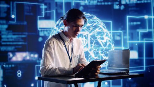 Side view of young woman using laptop at office