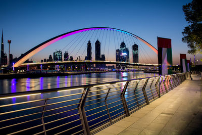 Illuminated bridge over river at night