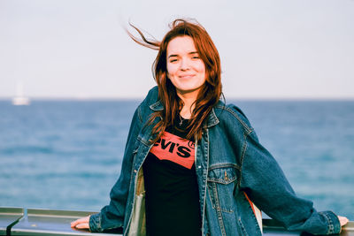 Smiling young woman against sea against sky