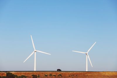 Wind turbines on field against clear sky