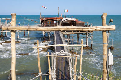 Wooden posts in sea against clear sky