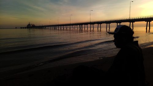 Silhouette man at beach against sky during sunset