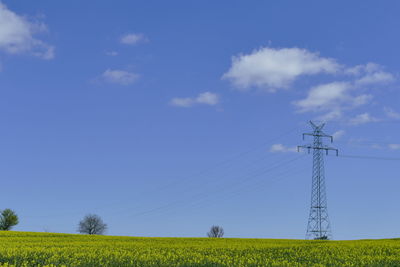 Low angle view of electricity pylon against blue sky