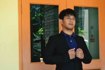 Young man standing against window