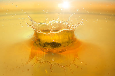 Close-up of water splashing against yellow during sunset