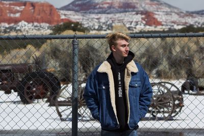 Young man looking through chainlink fence