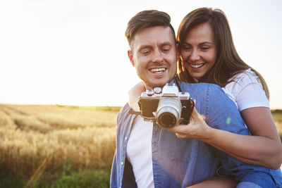 Smiling couple looking camera on land against clear sky