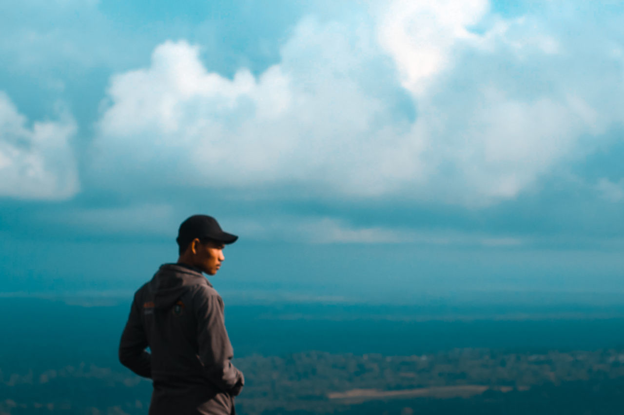 REAR VIEW OF MAN LOOKING AT VIEW OF SKY