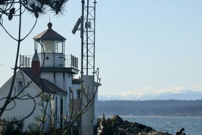 Lighthouse by sea against sky