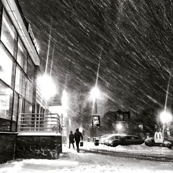 People walking on illuminated street during winter at night