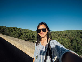 Portrait of smiling woman against clear blue sky