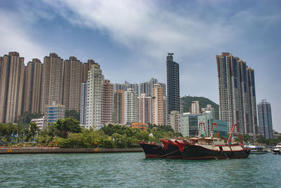 Modern buildings by river against sky in city